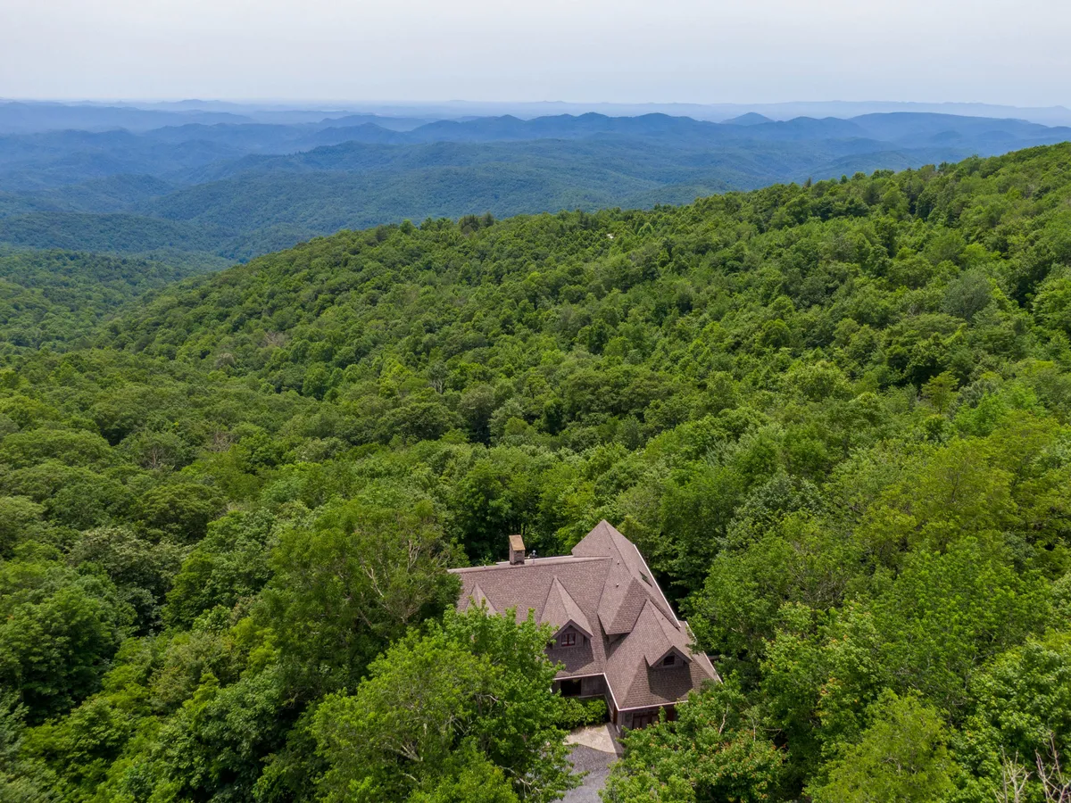 A wide exterior shot of the home nestled amid a lush forest, with a stunning mountain range visible in the background. The natural setting offers a sense of peace and seclusion, ideal for outdoor activities and exploration.