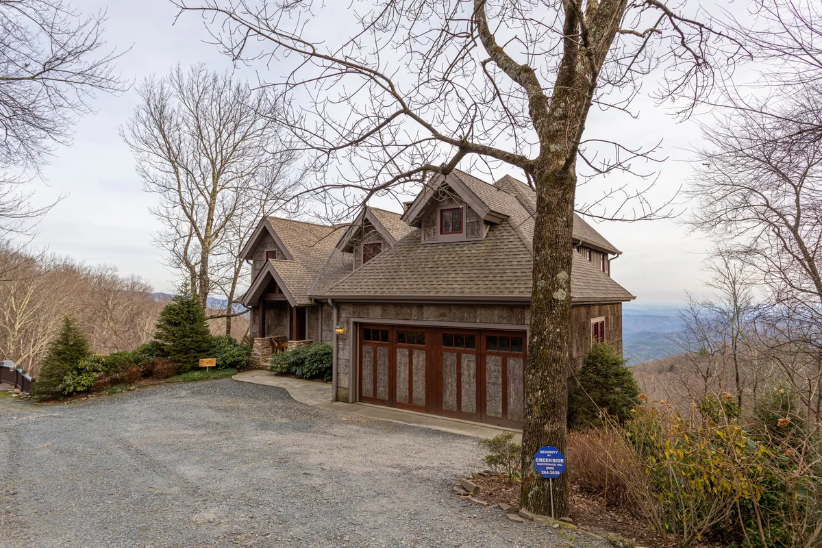 This exterior shot highlights the house's facade, spacious driveway, and the natural setting of surrounding trees. The open driveway offers ample space for multiple vehicles, reinforcing the practicality of group travel. The natural scenery suggests a peaceful, secluded setting ideal for relaxing after exploring local breweries and attractions.